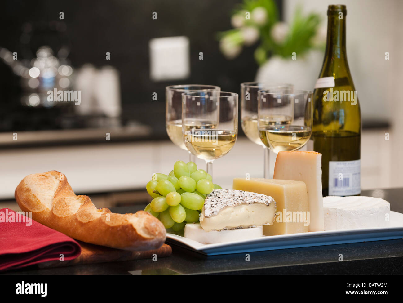 Cheeses and wine on kitchen worktop Stock Photo