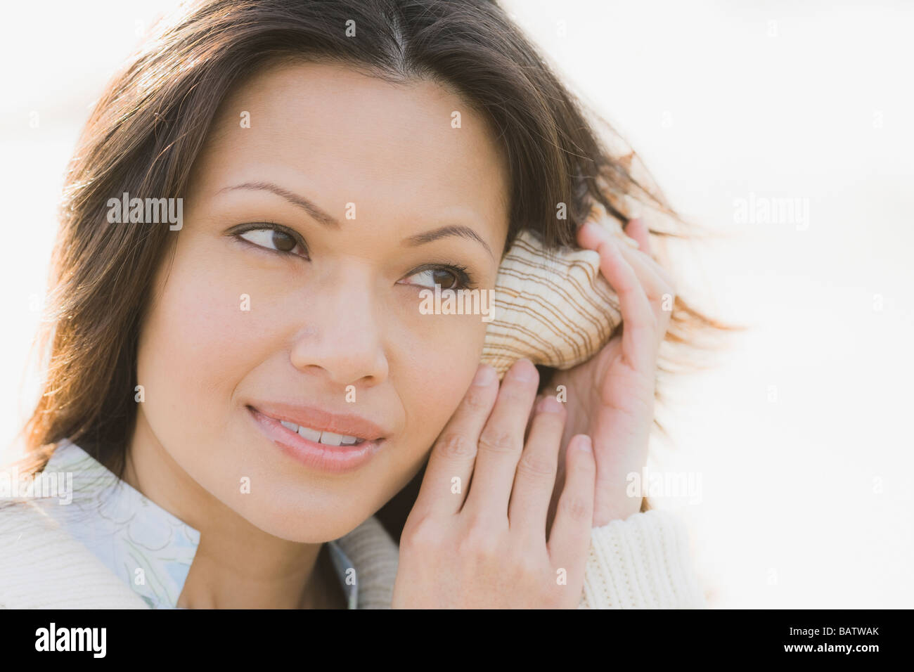 Close-up of woman listening to shell Stock Photo - Alamy