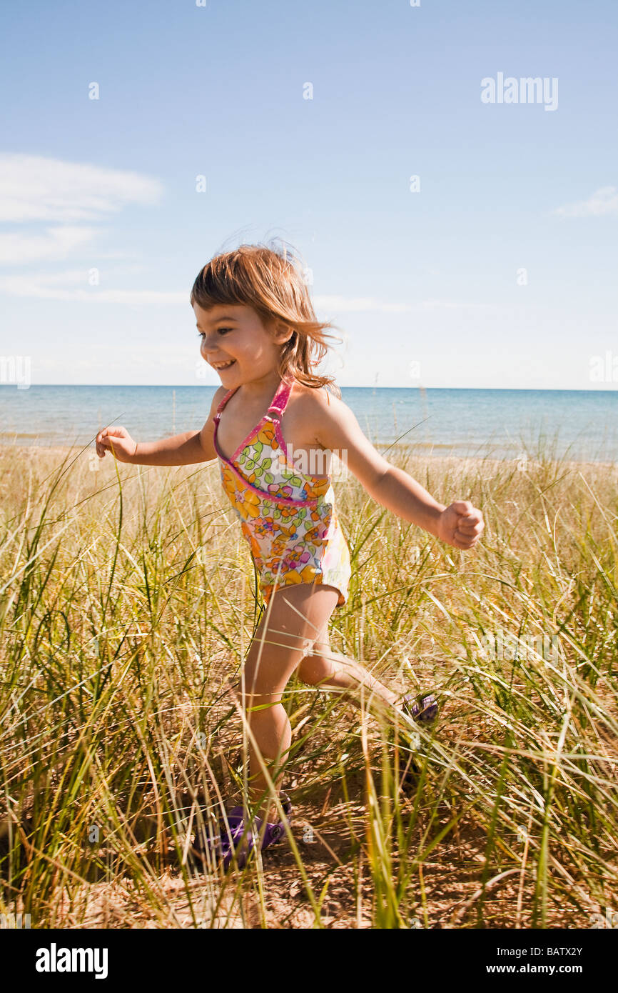 USA, Michigan, Beaver Island, Girl running in grass on beach Stock