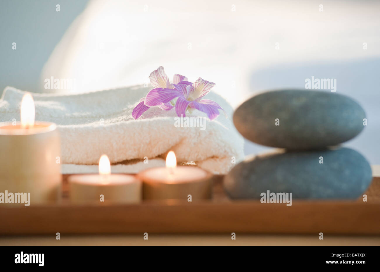 Rocks and candles on tray with woman lying in background Stock Photo