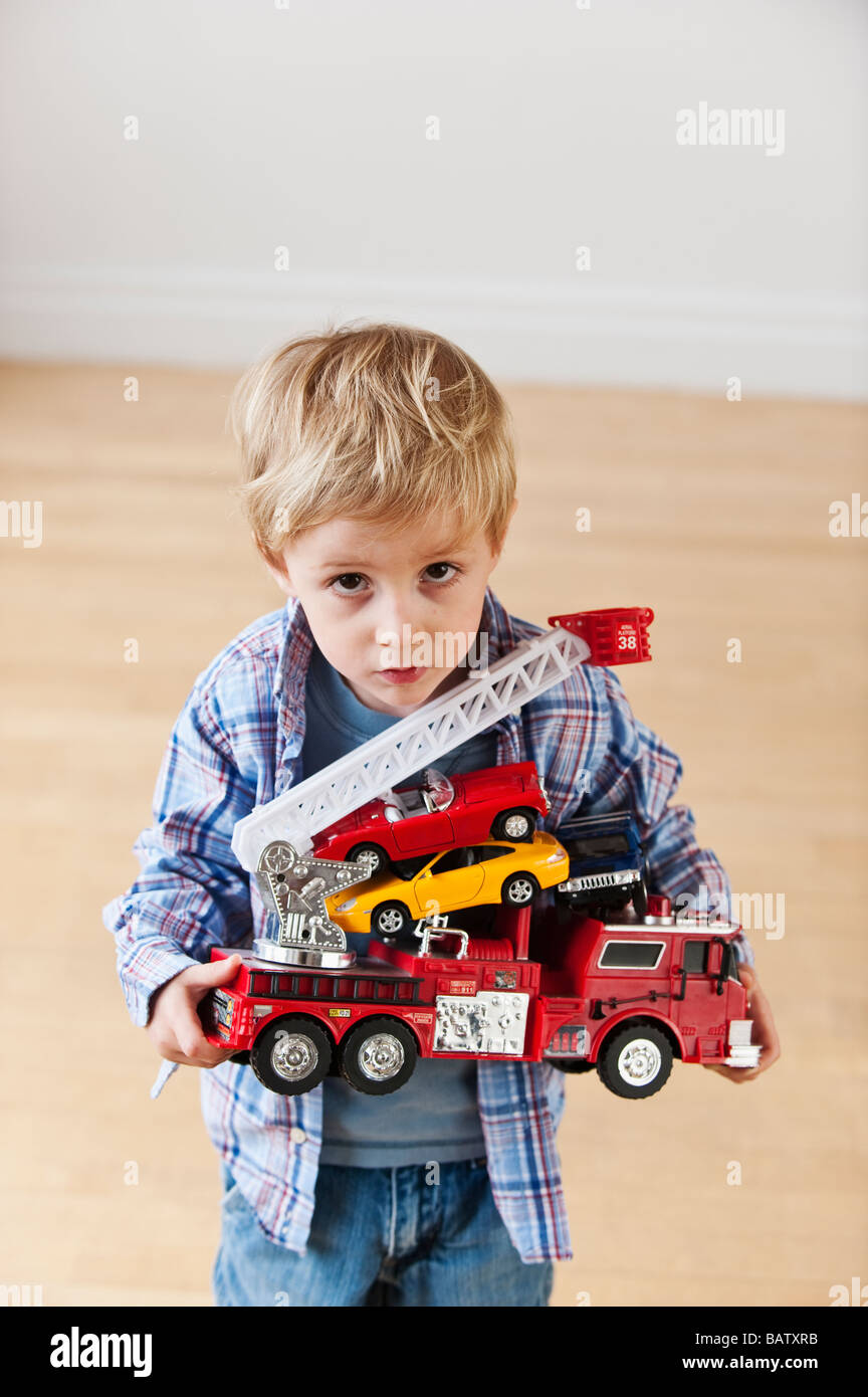 Portrait of boy (4-5) holding toy fire engine and cars Stock Photo
