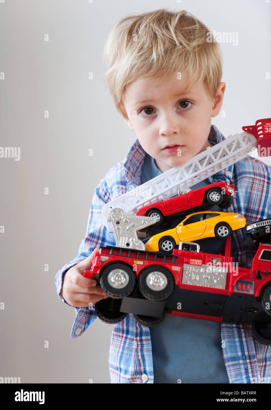 Portrait of boy (4-5) holding toy fire engine and cars Stock Photo