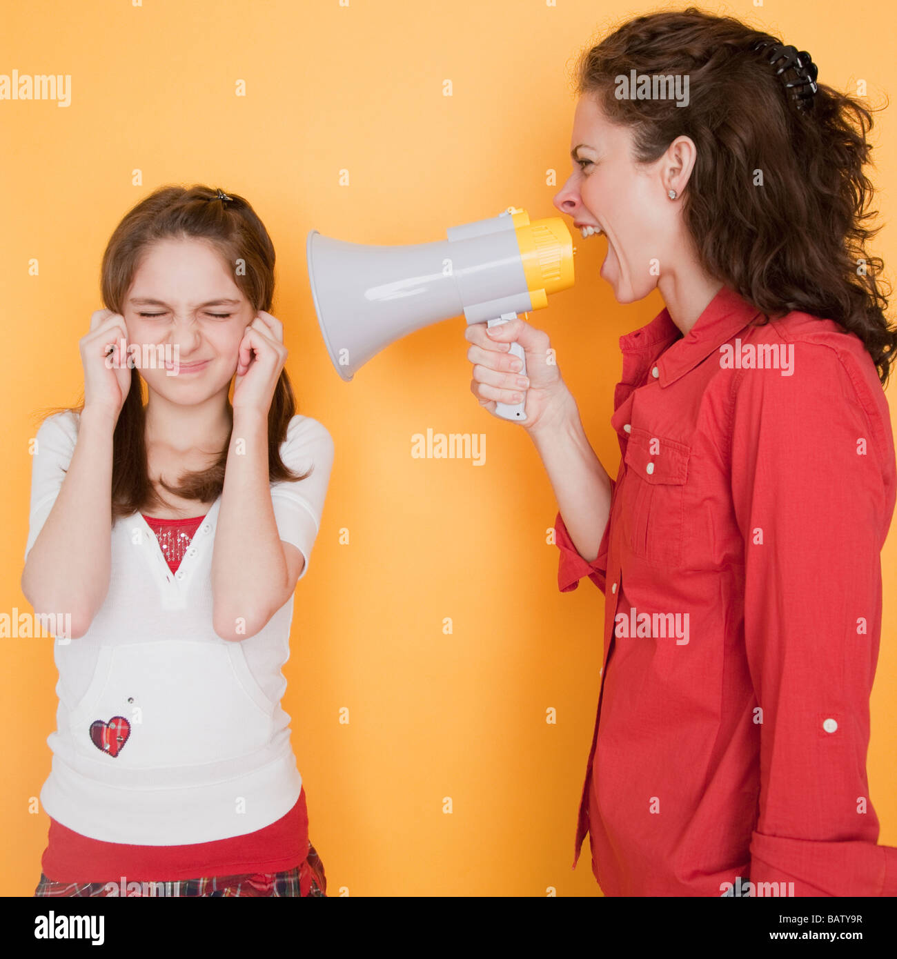 Mother yelling at daughter (1011 years) through megaphone Stock Photo