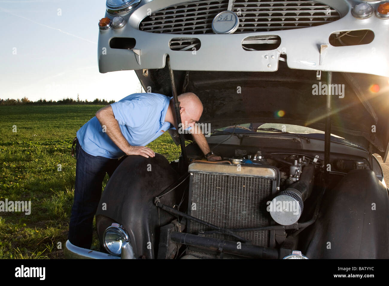 man repairing his classic car on empty road Stock Photo - Alamy