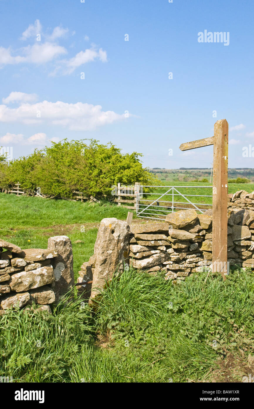 Footpath sign and squeeze stile in a dry stone wall. Stock Photo