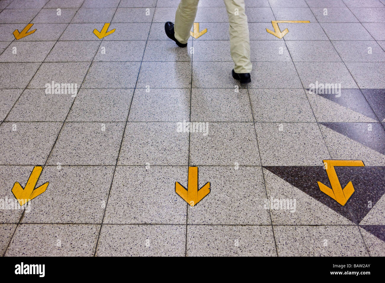 Yellow arrows on floor, walking against the stream Stock Photo