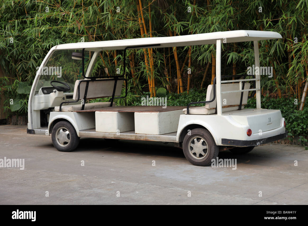 minivan to carry people in a parc or in a golf court. White empty vehicle waiting for visitors for a sightseeing forest Stock Photo