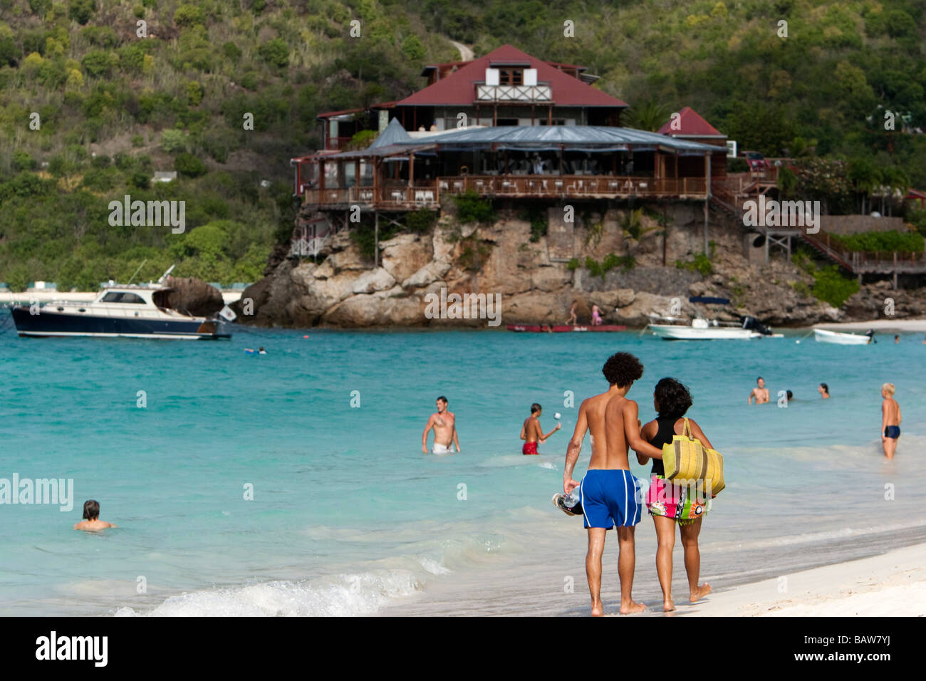 Young couple stroll beach at Baie de St Jean Eden Rock Hotel in distance St Barts Stock Photo