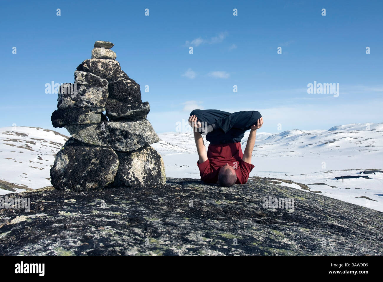 Doug Blane performing an Urdhva Padmasana besides a cairn in Finse Norway in winter Stock Photo