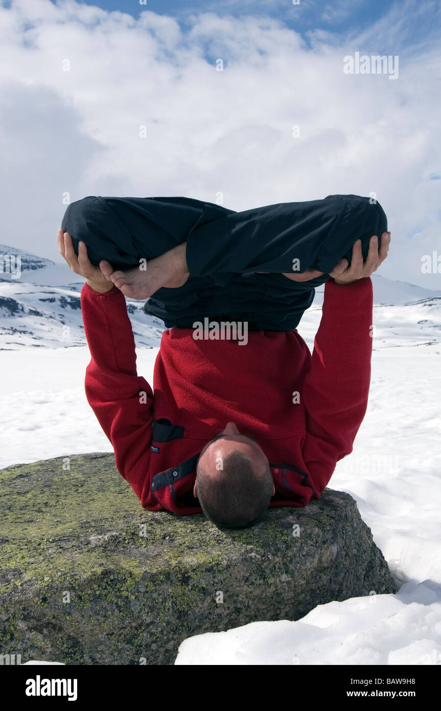 Doug Blane performing an Urdhva Padmasana yoga, upside down lotus on frozen Finse Vatn lake, Finse, Norway Stock Photo