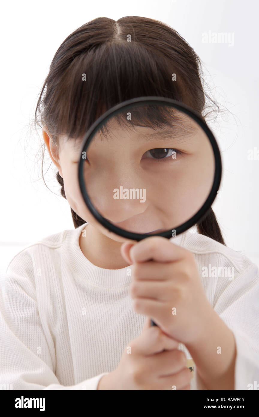 Girl holding magnifying glass to her face Stock Photo