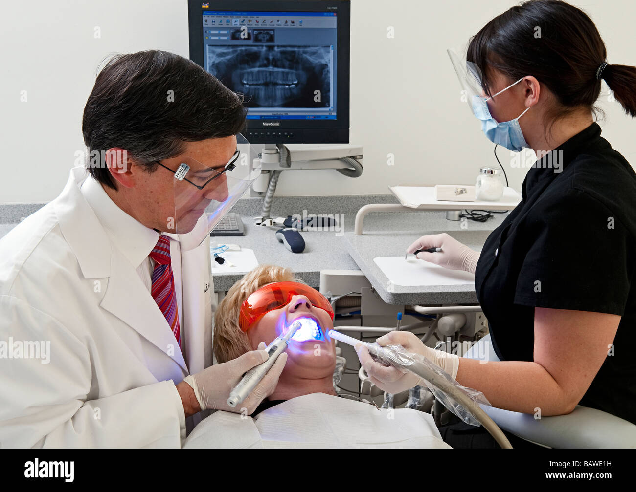 Dentist and assistant work on a patient Stock Photo