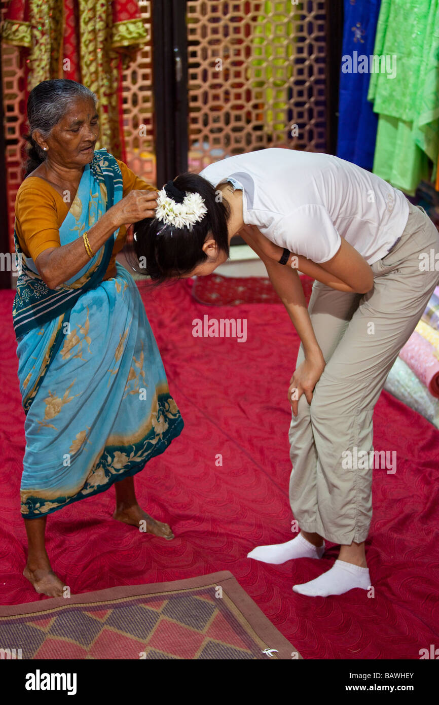 Indian Woman Putting Flowers in the Hair of a Chinese Tourist in Mumbai Delhi Stock Photo