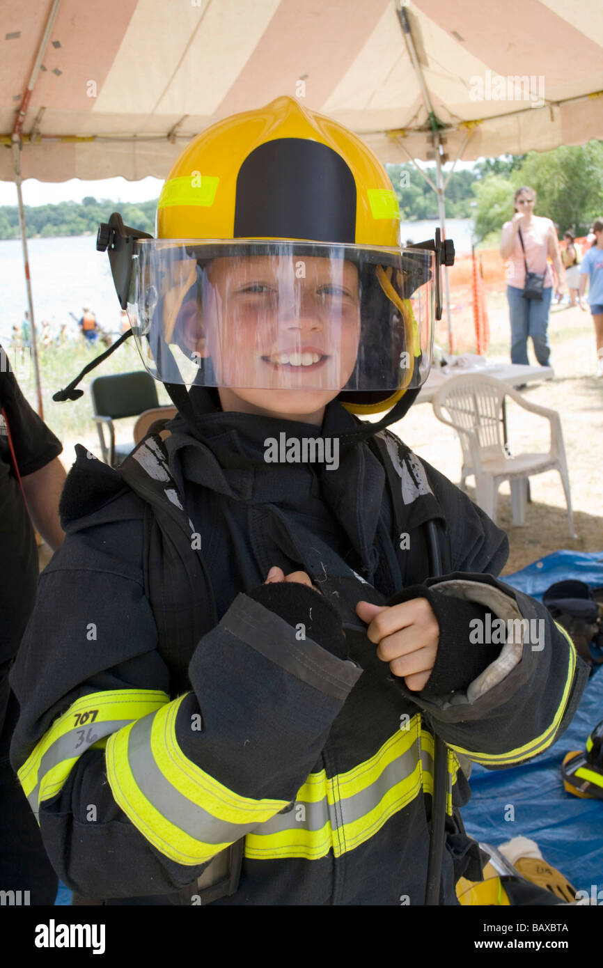 Boy age 11 wearing firefighter jacket and helmet at rescue demonstration. Aquatennial Beach Bash