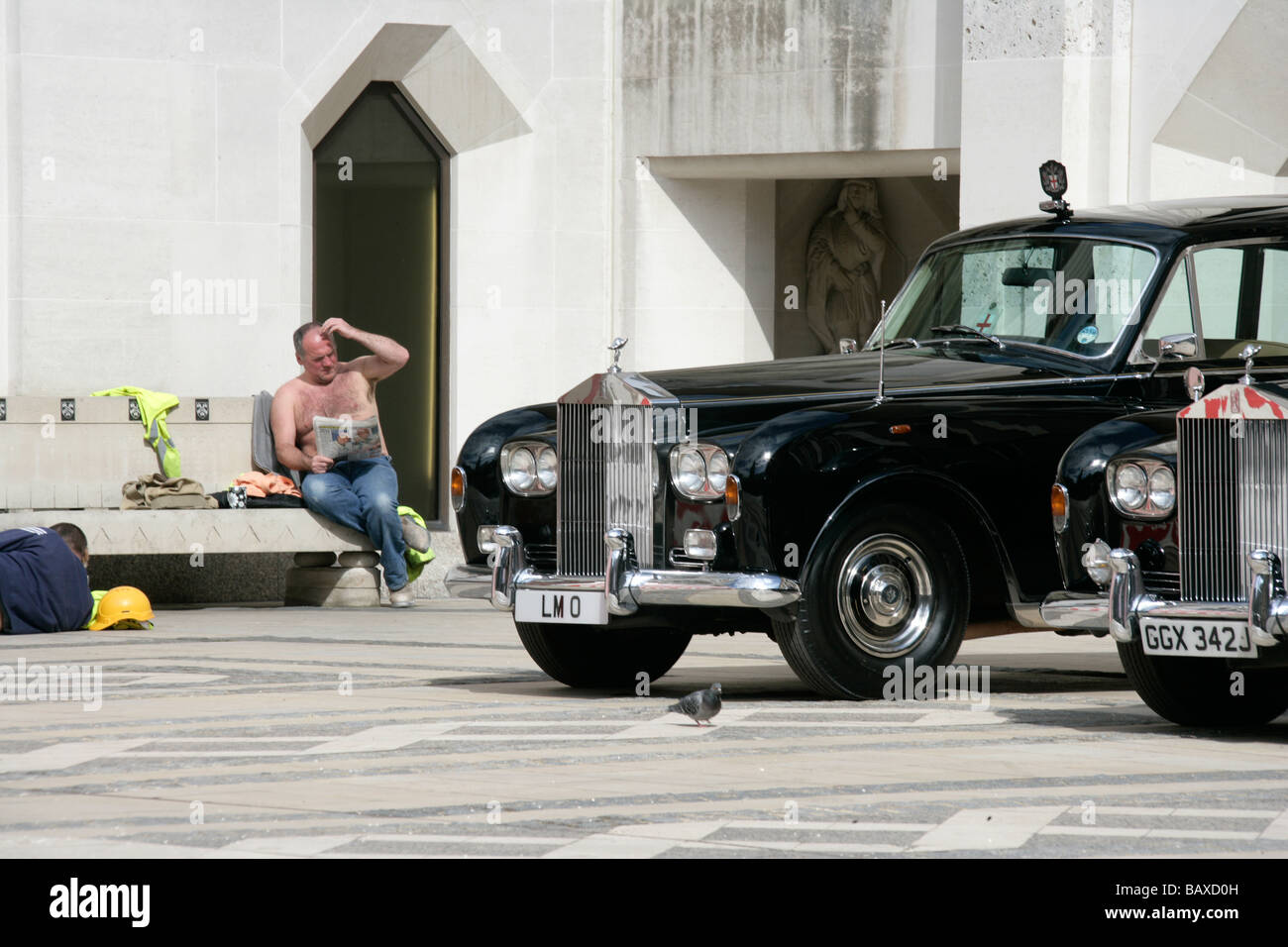 Two Rolls Royce Phantom VIs stand proud next to that other Great British Institution, the British workers beer belly Stock Photo