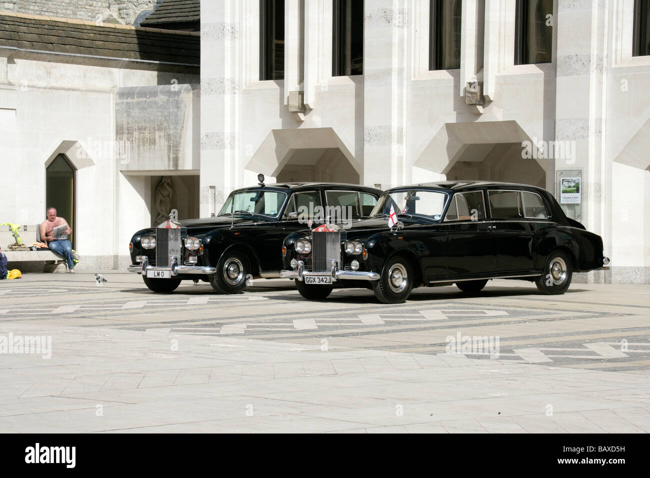 Two Rolls Royce Phantom VIs stand proud next to that other Great British Institution, the British workers beer belly Stock Photo