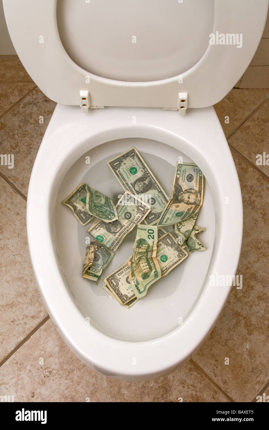 A pile of money getting ready to be flushed down the toilet Stock Photo
