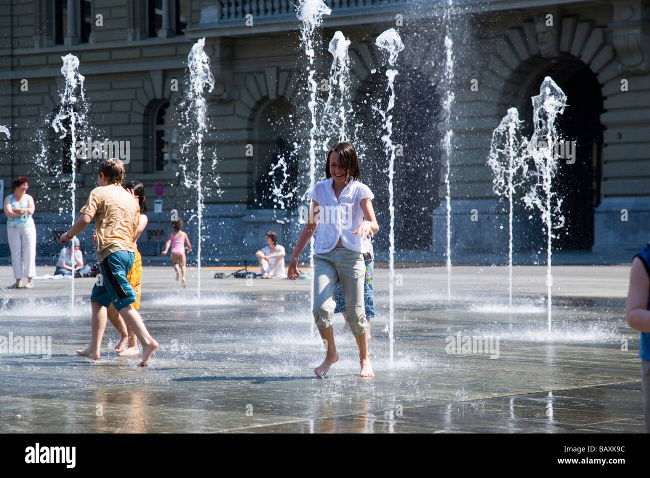 Children playing in the trick fountains and water gardens in front of the House of Parliament on Parliament Square, Bundeshaus, Stock Photo