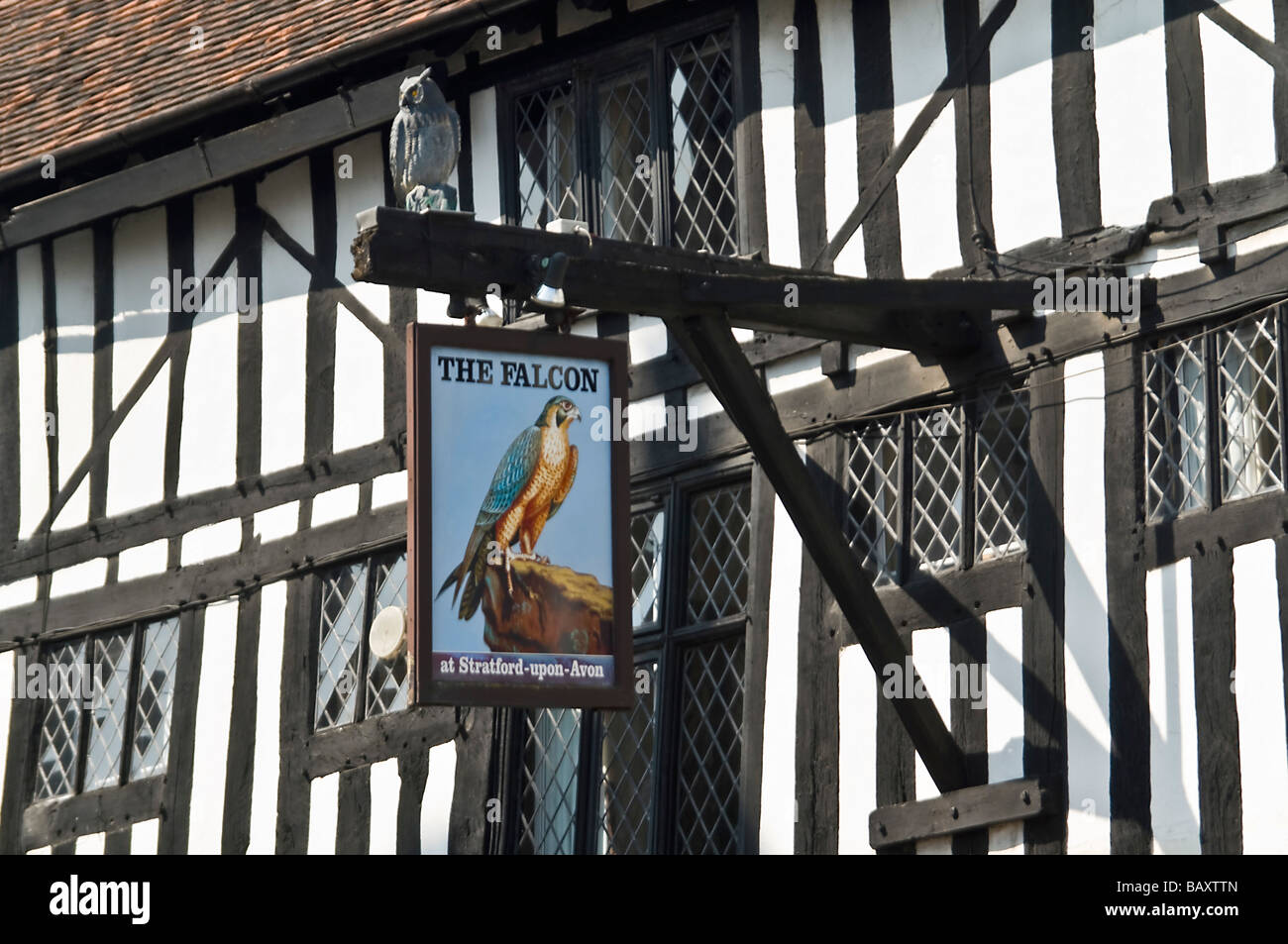 Horizontal close up of an old black and white Tudor building with a decorative pub sign hanging outside on a bright sunny day Stock Photo