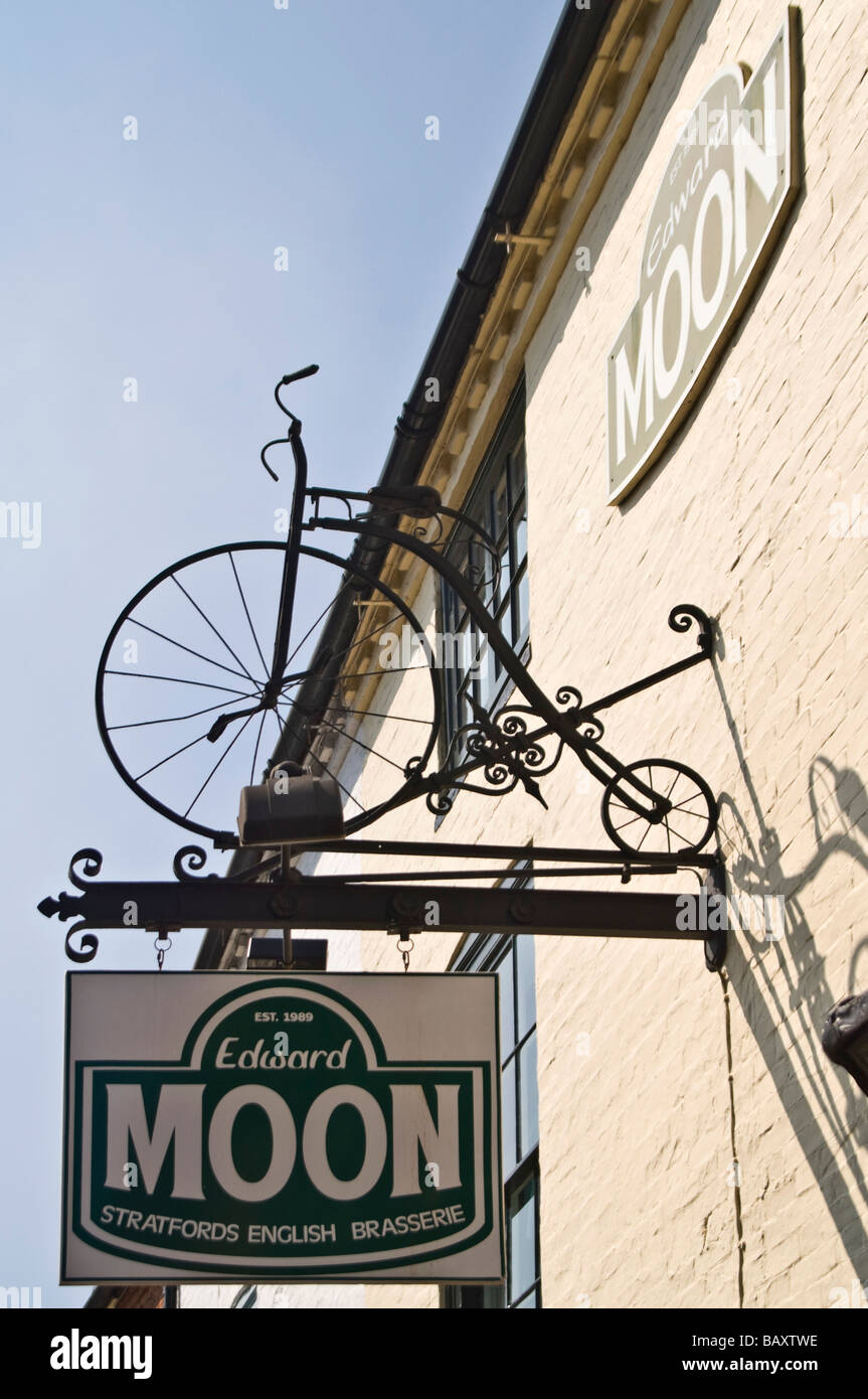 Vertical close up of an elaborate Penny Farthing bicycle wrought iron restaurant sign hanging against a bright blue sky Stock Photo