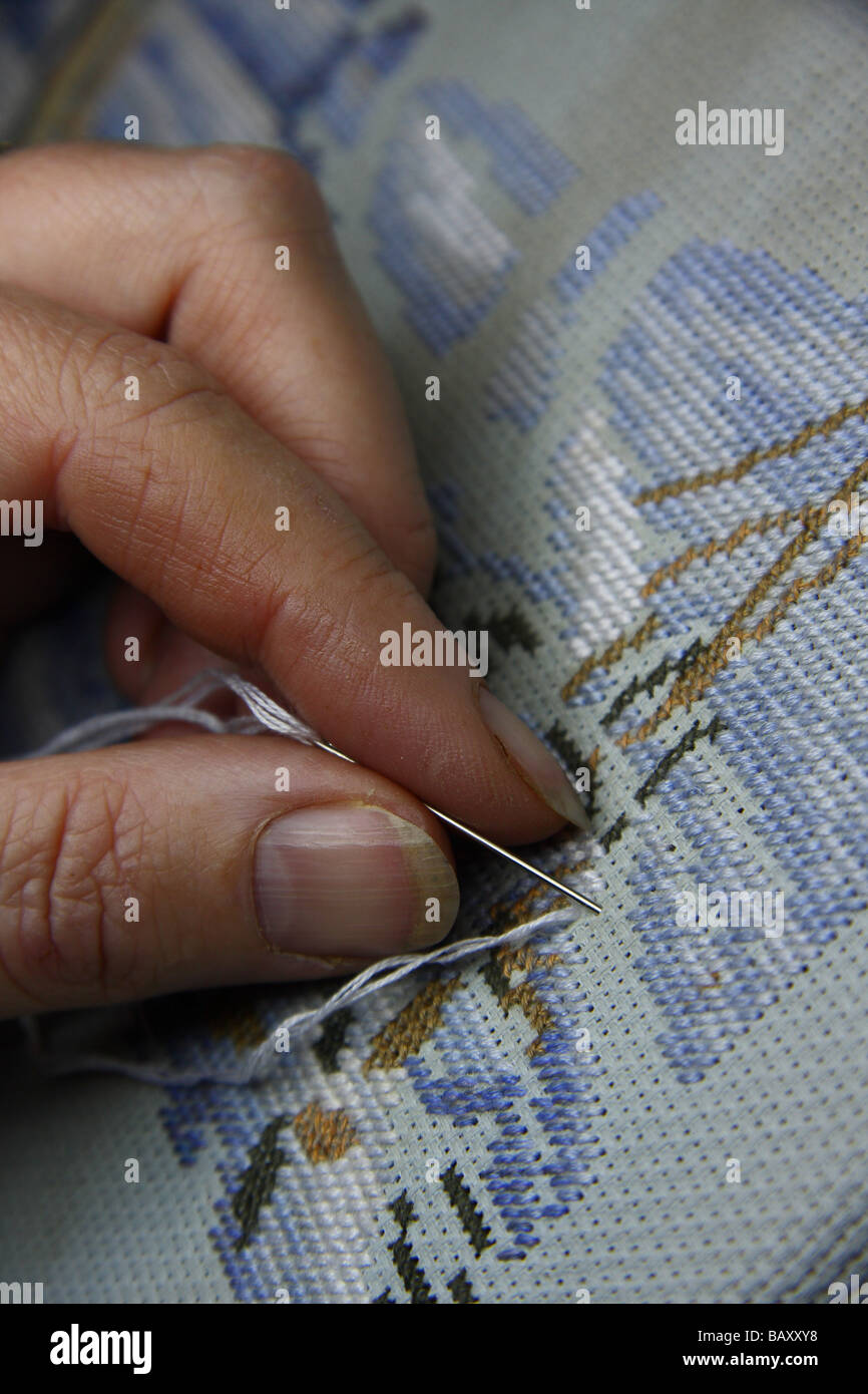 close up of a woman's fingers working on a cross stitch Stock Photo