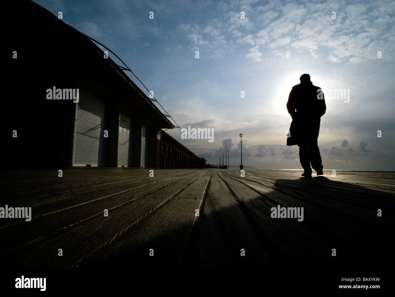Man walking along lonely boardwalk, Deauville, France Stock Photo