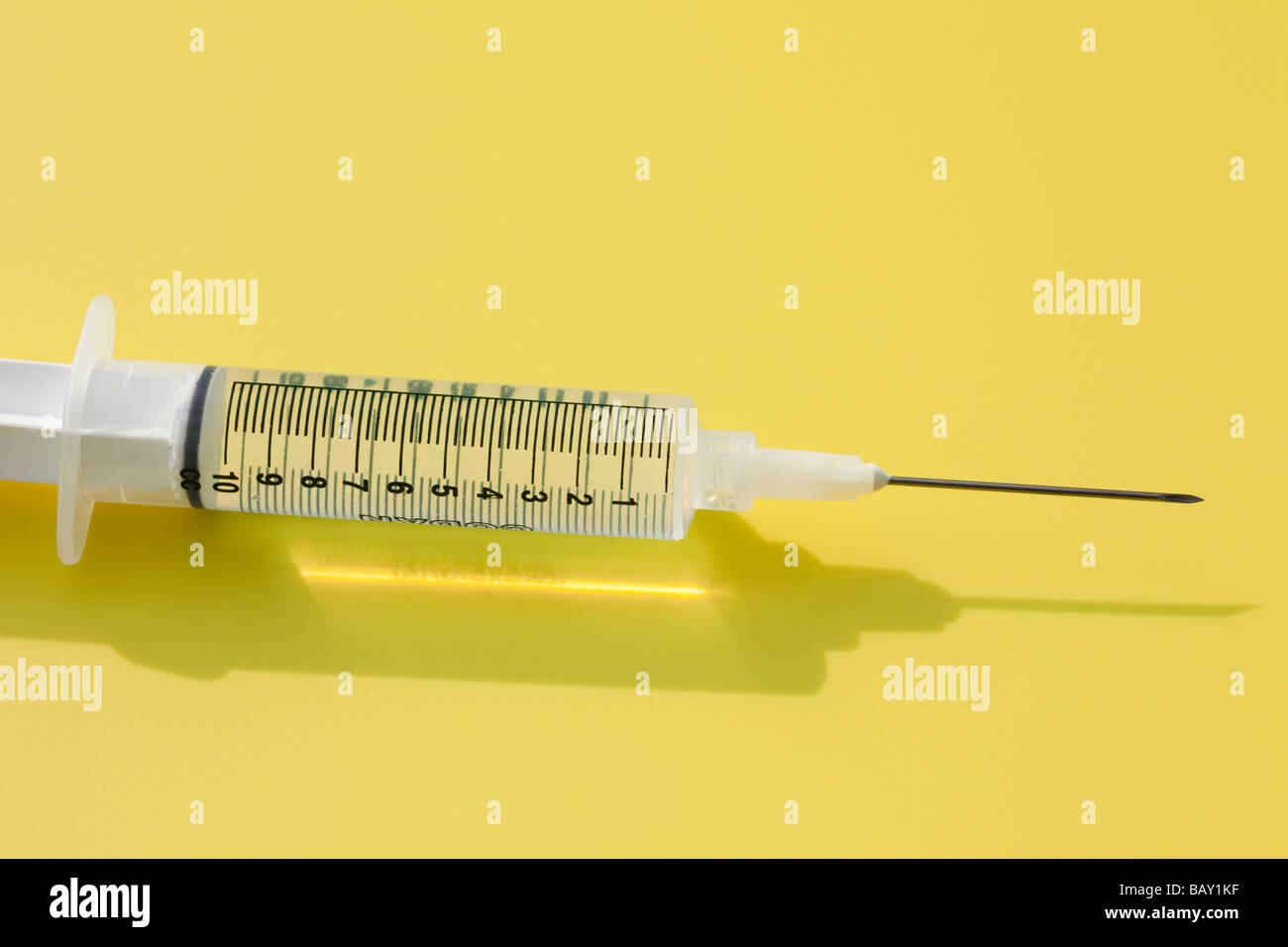 Studio still life 10 cc ml plastic syringe with needle in close up on a yellow background Stock Photo