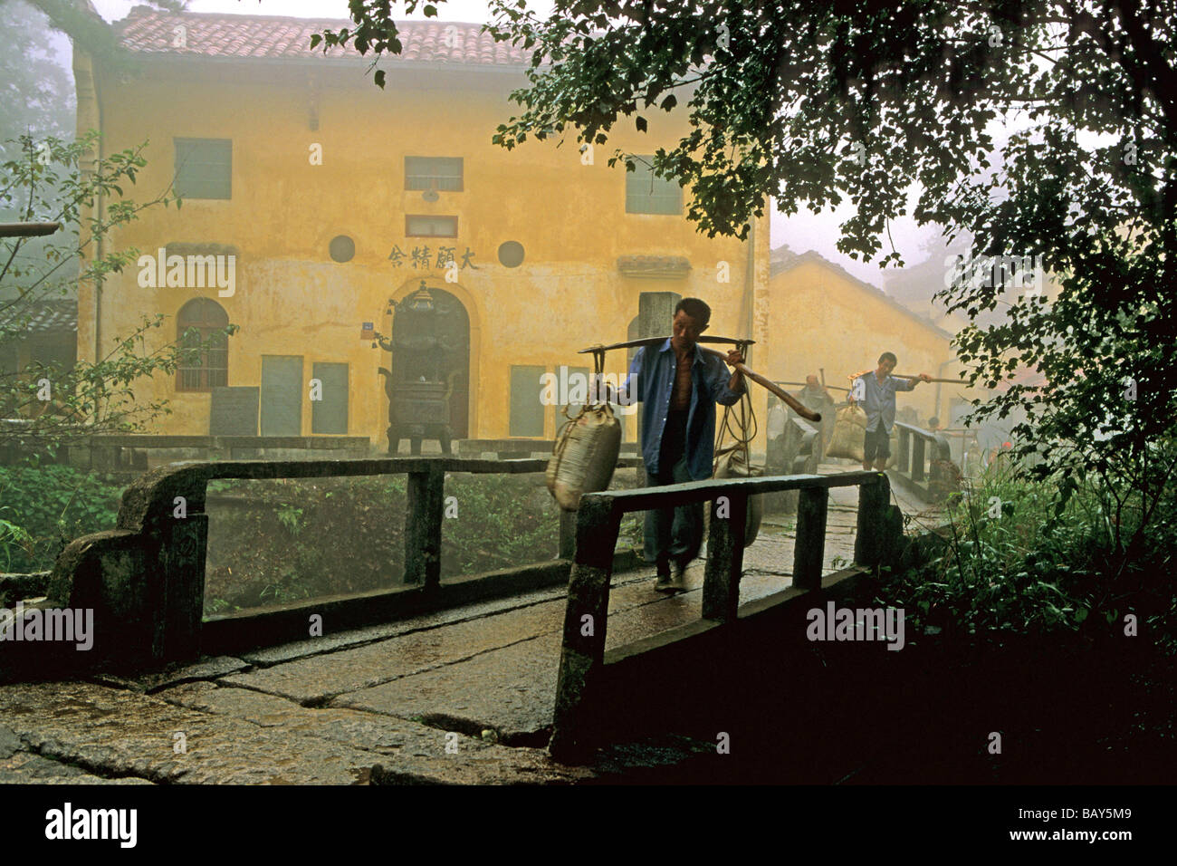 Porters carrying building material in front of Tianchi monastery at the village Jiuhuashan, Anhui province, China, Asia Stock Photo