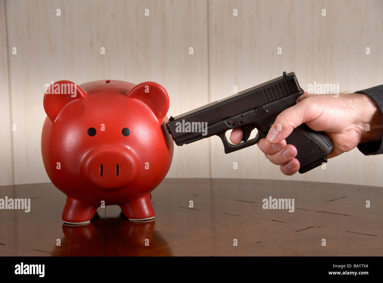 A man ready to take out his broke piggy bank with a loaded pistol Stock Photo