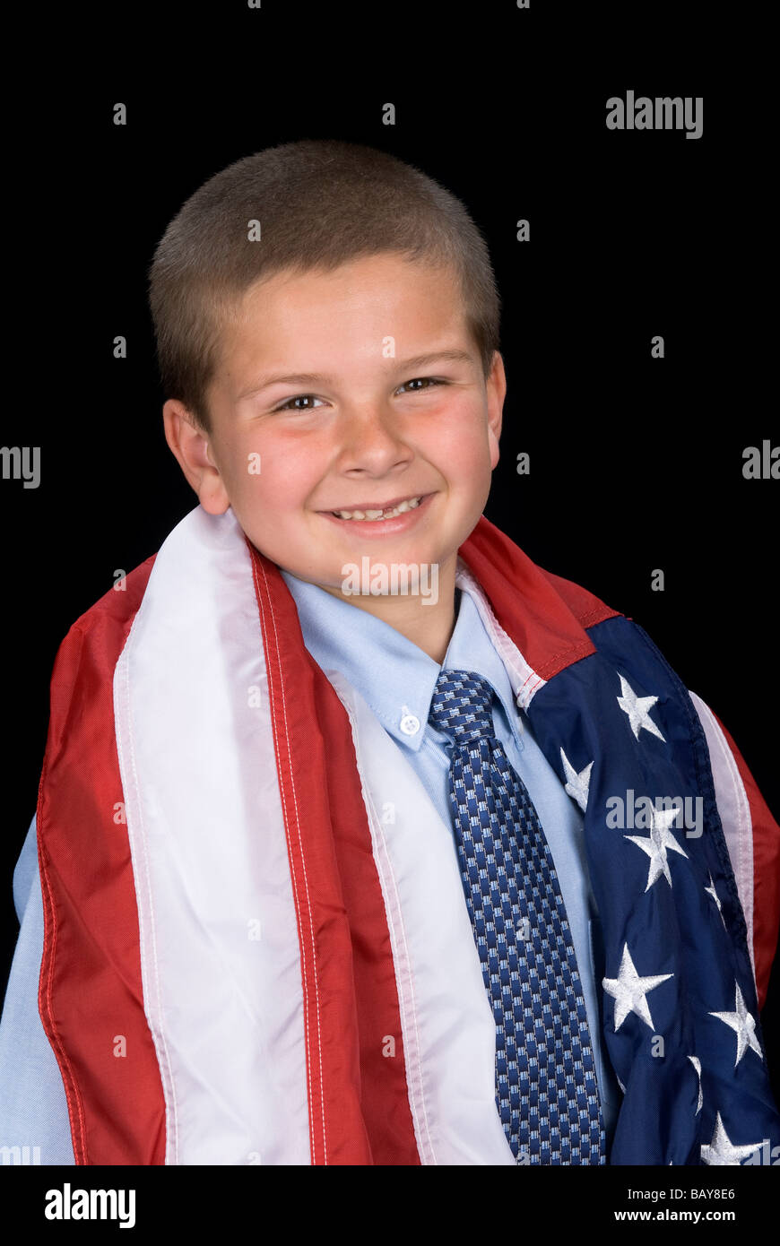 A young boy with a dress shirt and necktie has an American flag draped