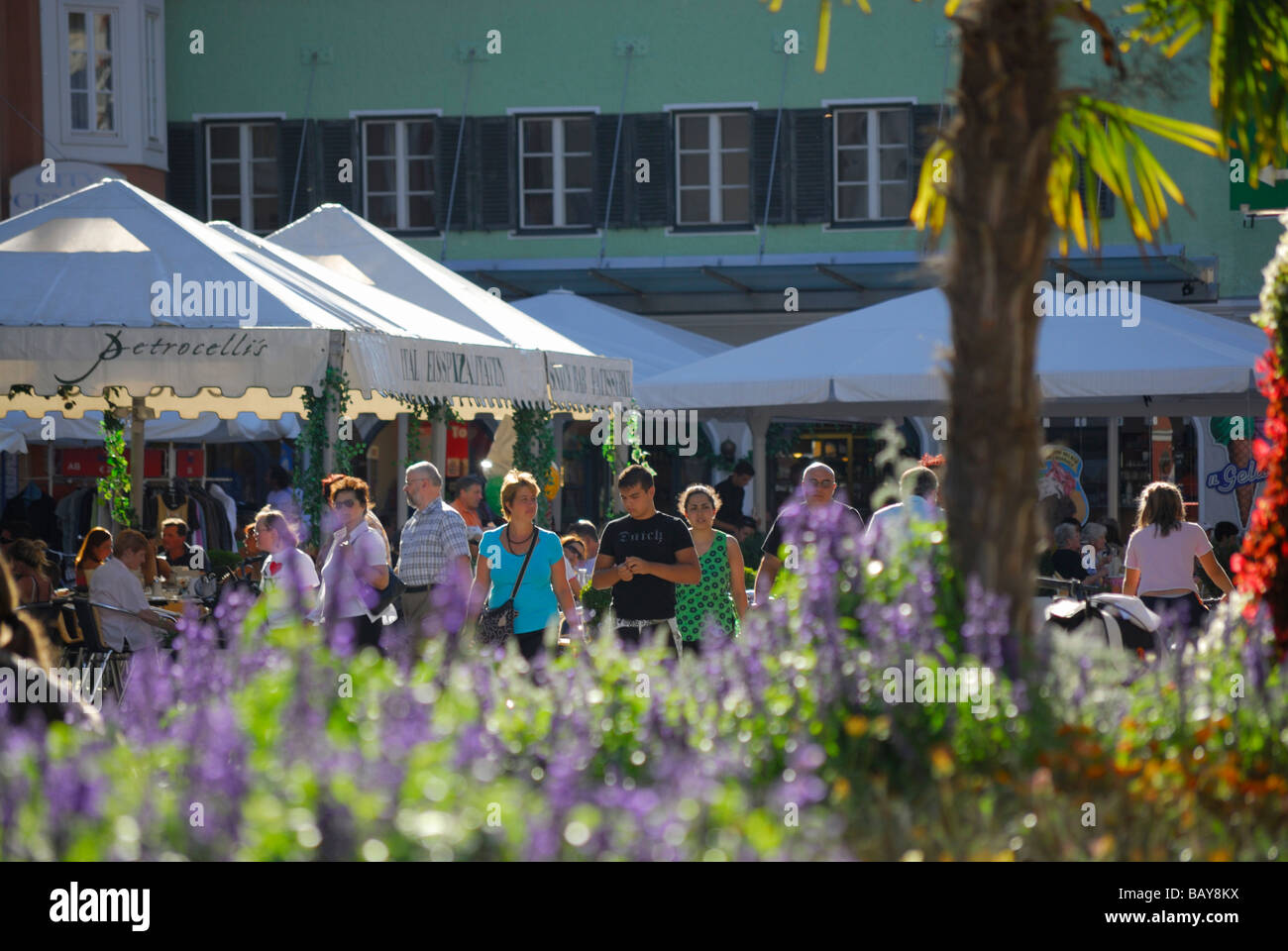 people at main place in city of Lienz, flower decoration out of focus in foreground, pedestrian zone, Lienz, East Tyrol, Austria Stock Photo