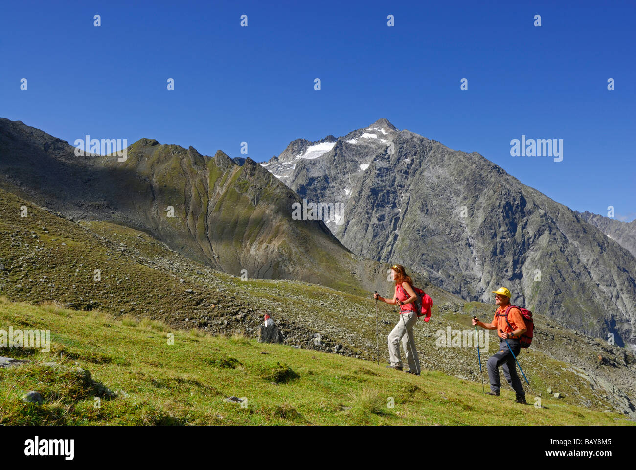 couple on trail through green meadow, Lisenser Fernerkogel in background, Luesener Fernerkogel, Sellrain range, Stubaier Alpen r Stock Photo