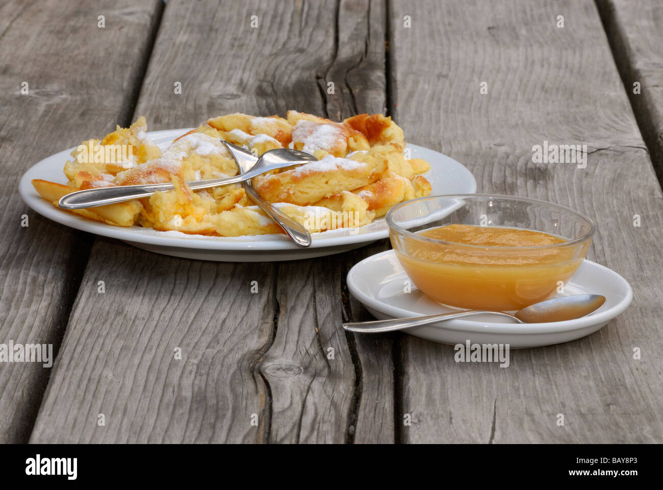 one portion of cut-up and sugared pancake with apple sauce on wooden table, alpine hut Sulzenaualm, Sulzaualm, Stubaier Alpen ra Stock Photo