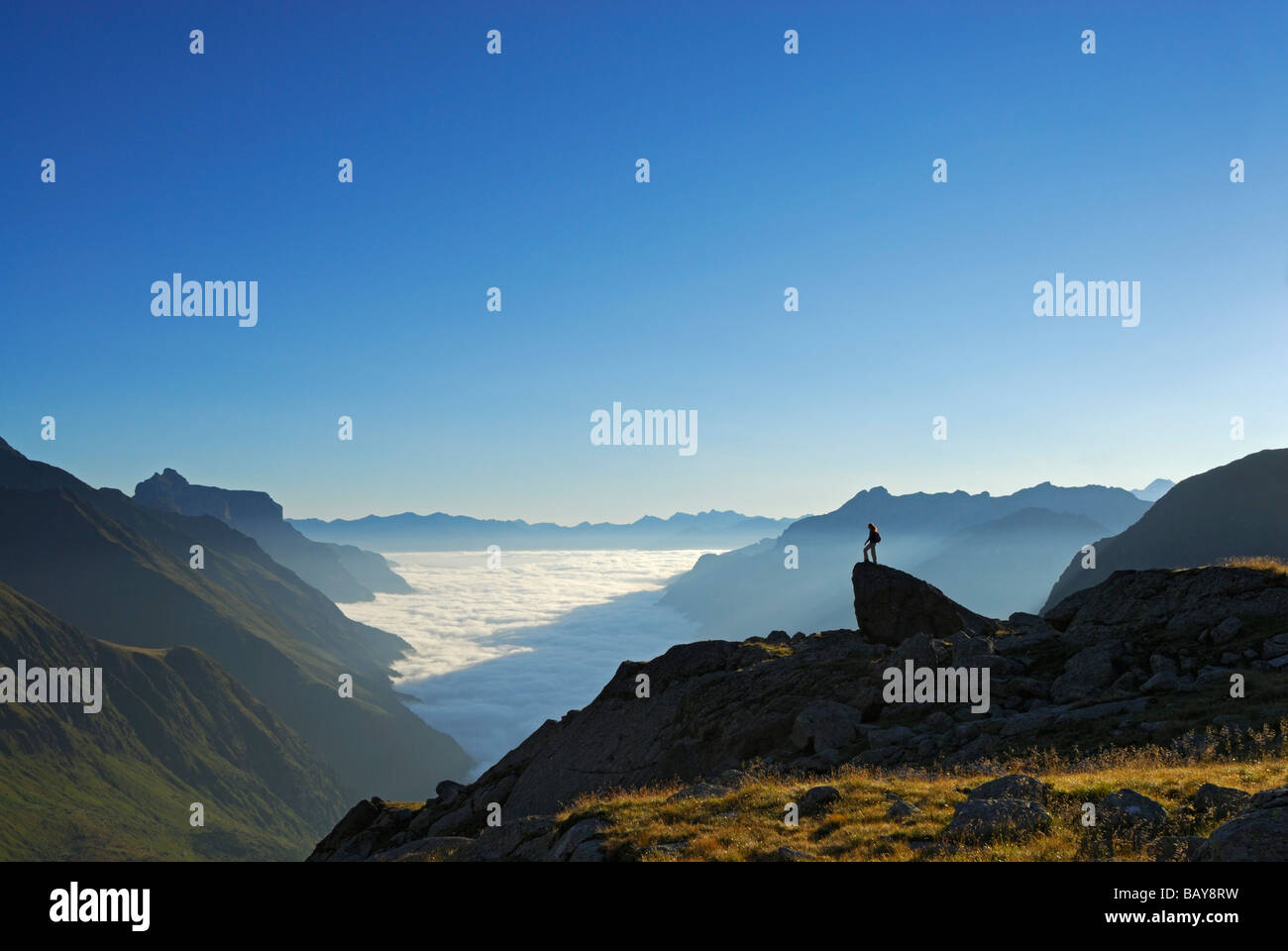 hiker on crag above fog bank in valley Gschnitztal, Kirchdachspitze in background, Bremer Huette, Stubaier Alpen range, Stubai, Stock Photo