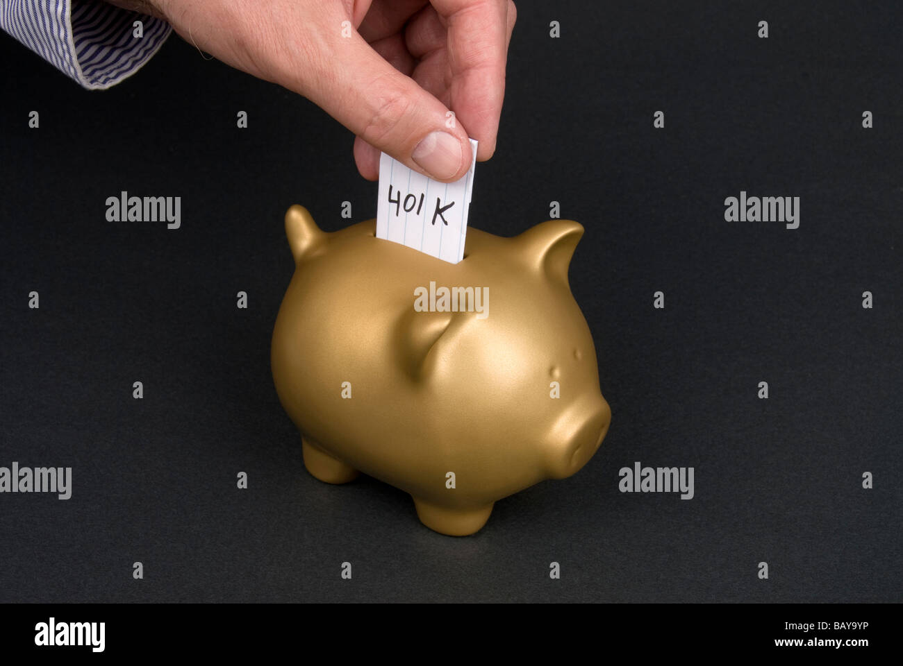 A man places a slip of paper into a piggy bank Stock Photo