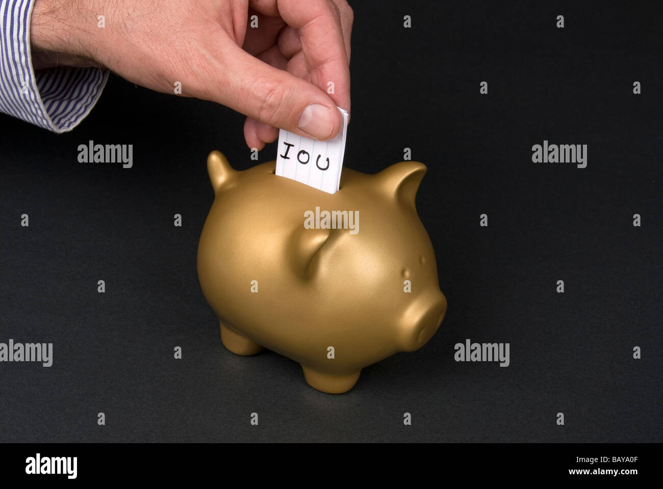 A man places a slip of paper into a piggy bank Stock Photo