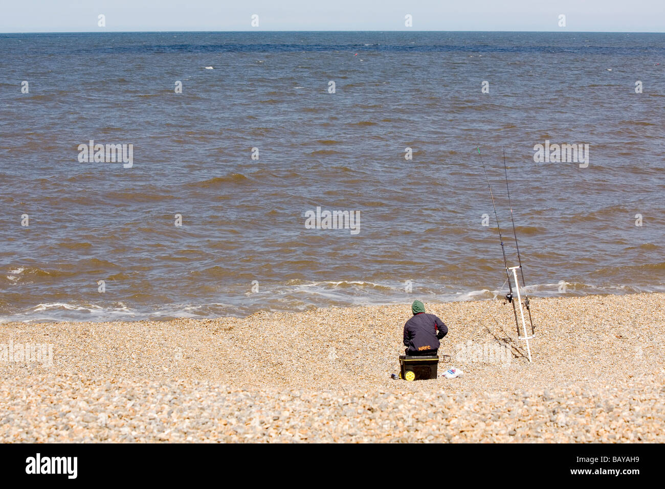 Lone angler on pebble beach North Norfolk coast Stock Photo