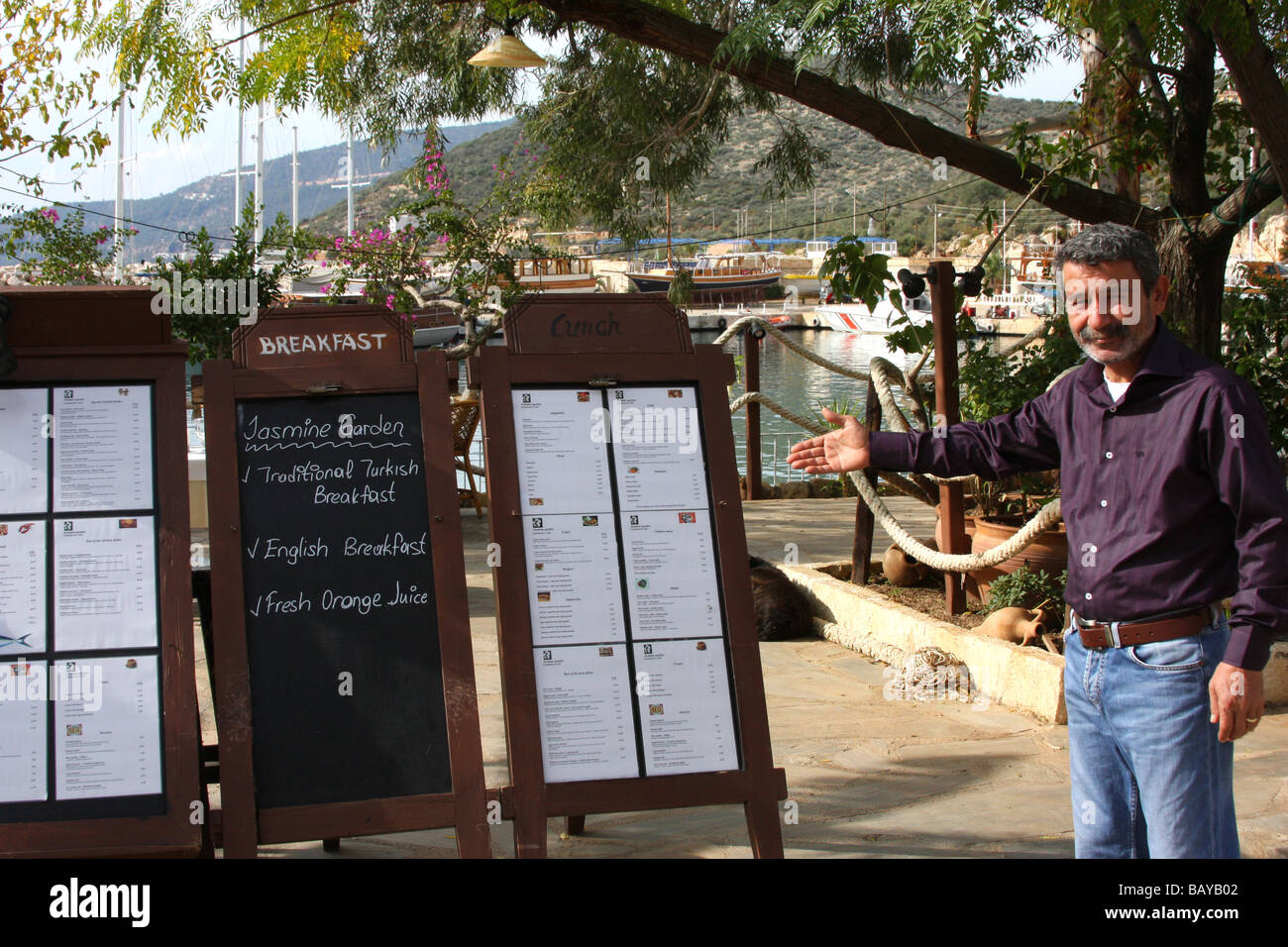 Restaurant owner in Kalkan, Turkey, inviting you to inspect his menu ...