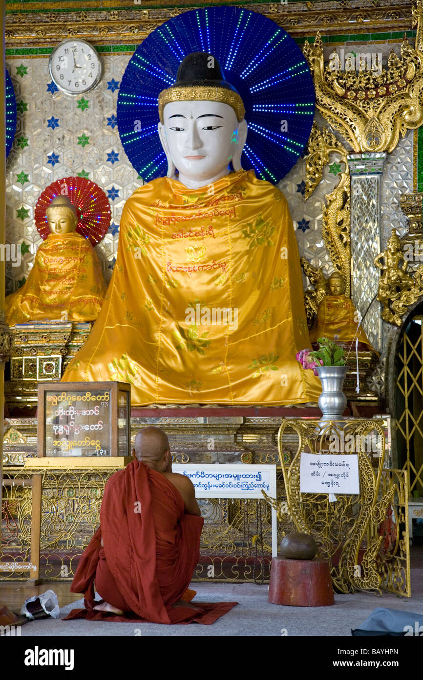 Buddhist monk worshiping Buddha. Shwedagon Paya. Yangon. Myanmar Stock