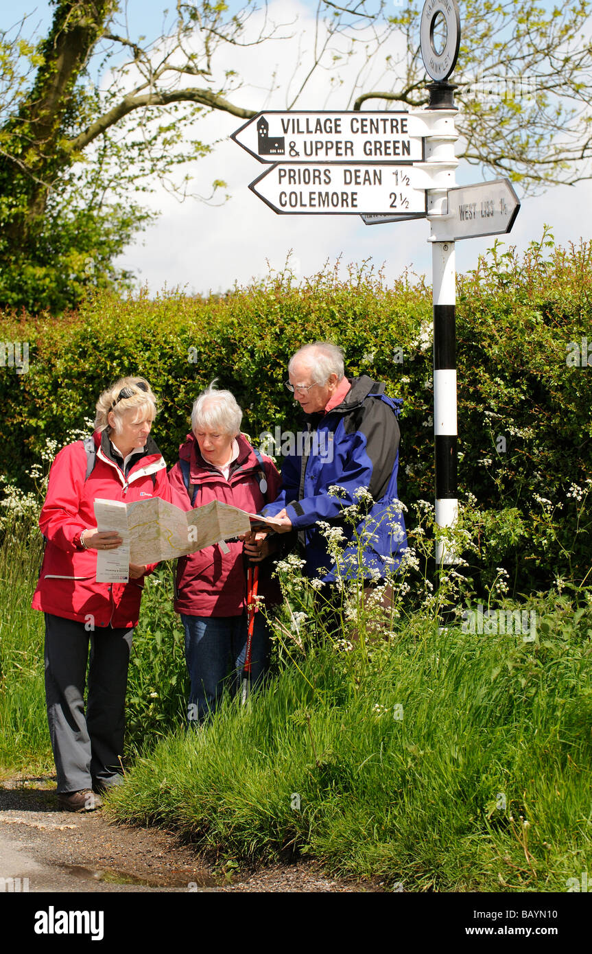Group of hikers pause to read their map and check the direction of travel seen in the Hampshire countryside in springtime Stock Photo