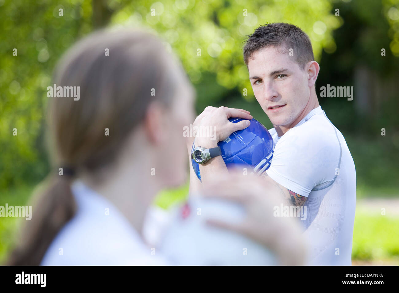 A physical training instructor with a female student during an exercise session outside in the English countryside Stock Photo