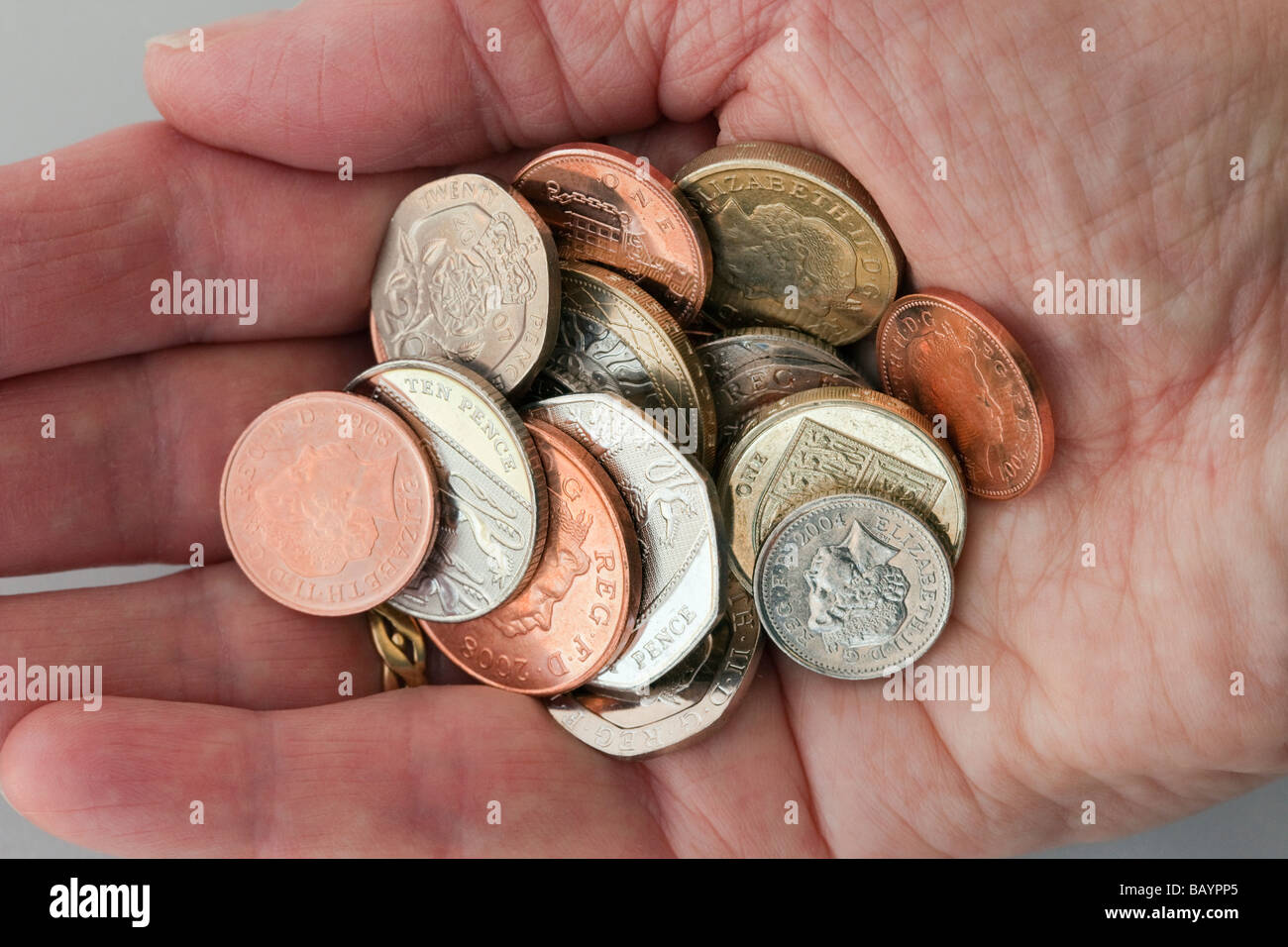 Pensioner holding a handful of Sterling money coins cash of low value in palm of an open hand to illustrate poverty in retirement austerity. UK Stock Photo