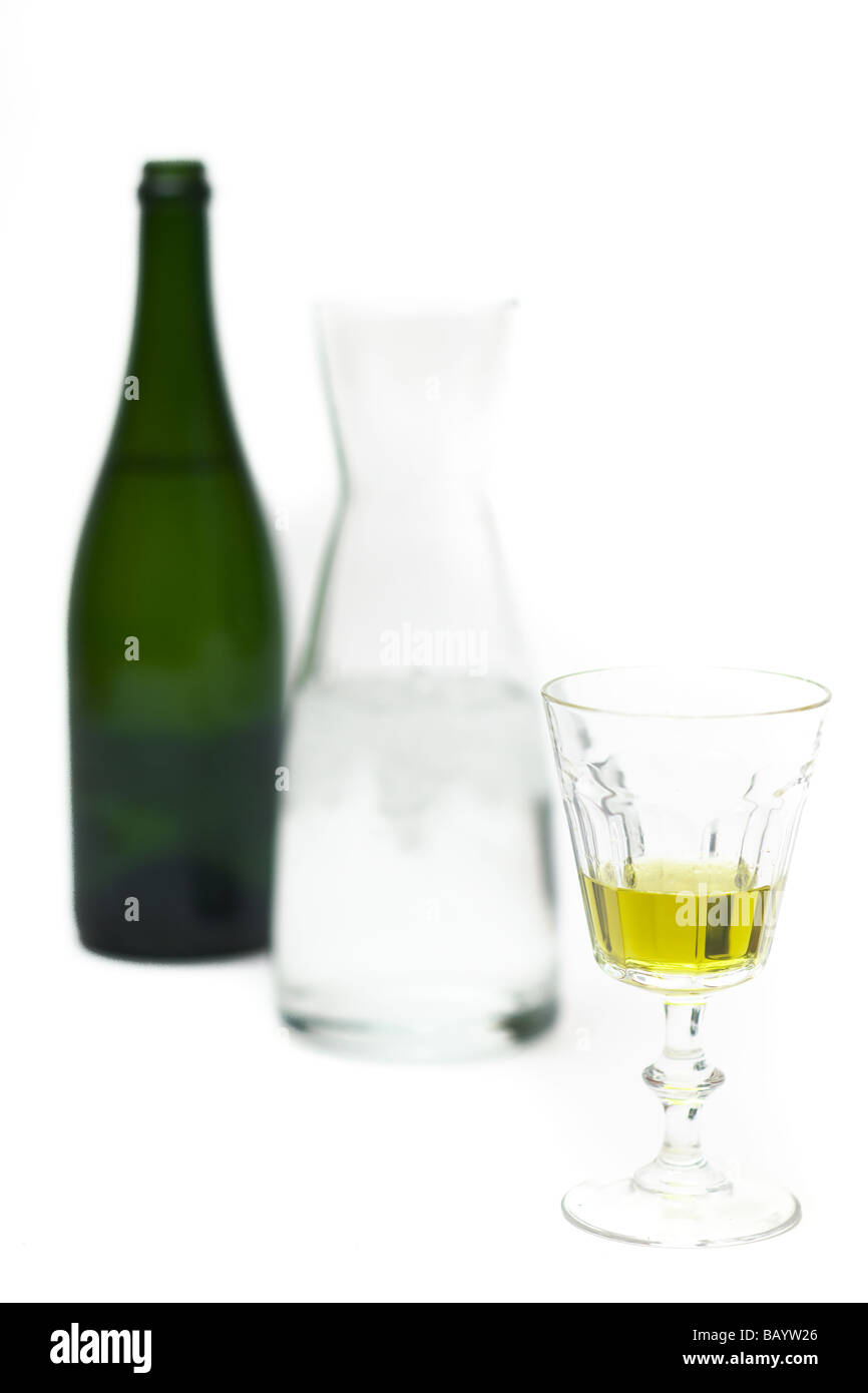 A glass of absinthe with a canister of ice water and an unidentifiable bottle. Stock Photo