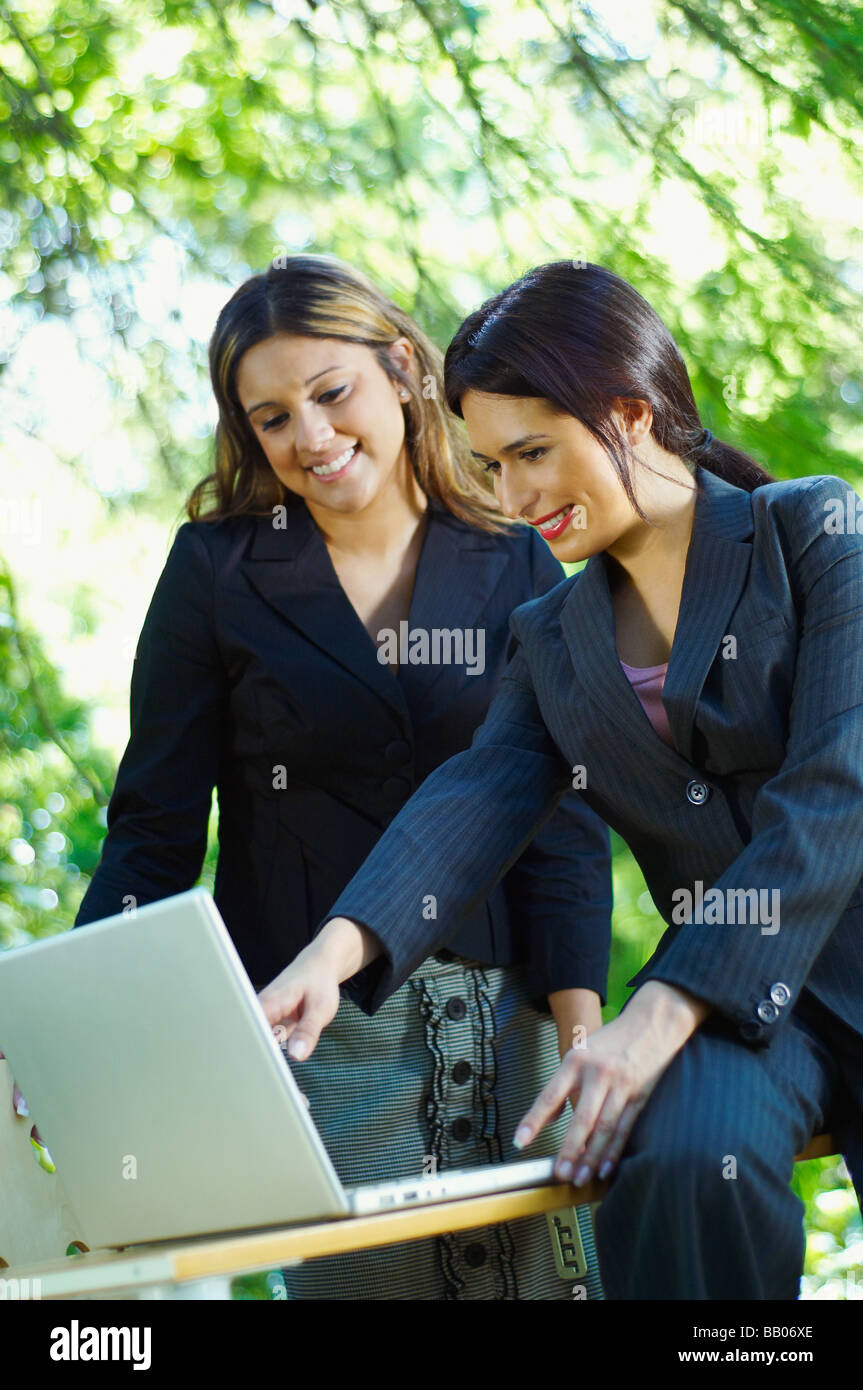 Hispanic businesswomen using laptop outdoors Stock Photo
