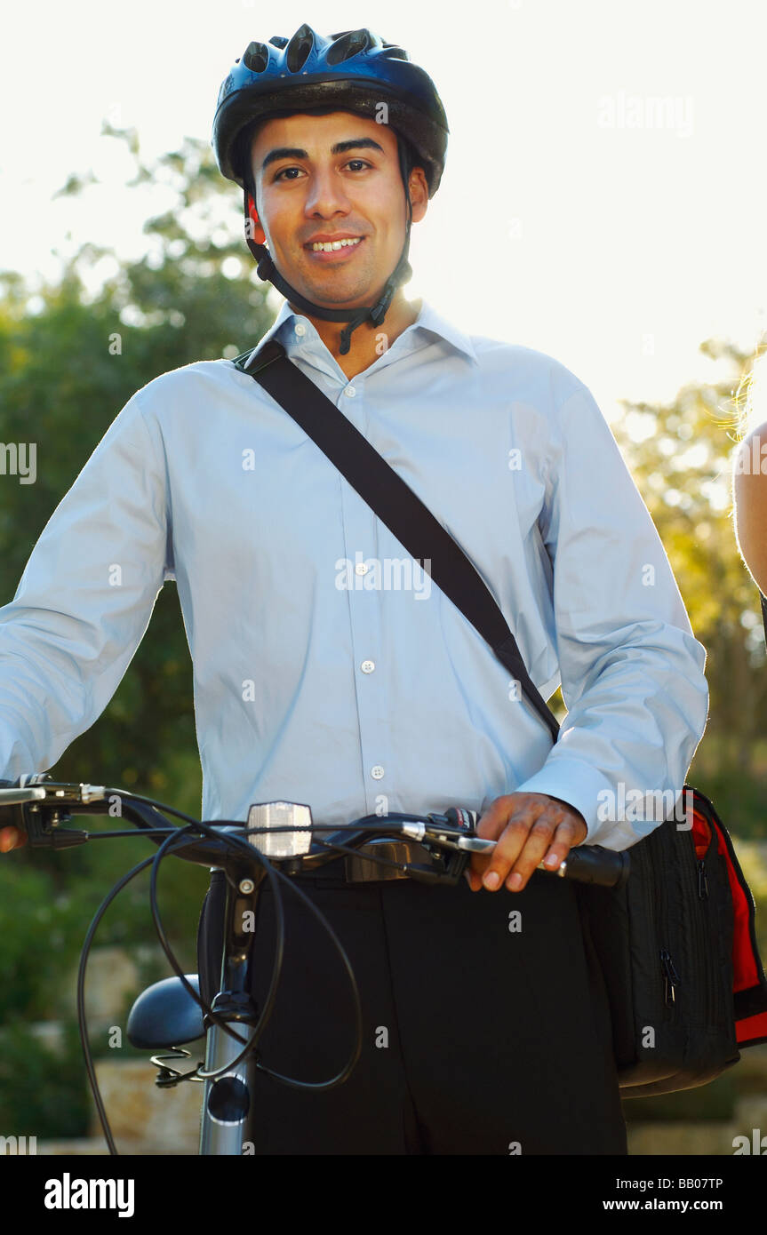 Hispanic businessman wearing bike helmet and holding bike Stock Photo