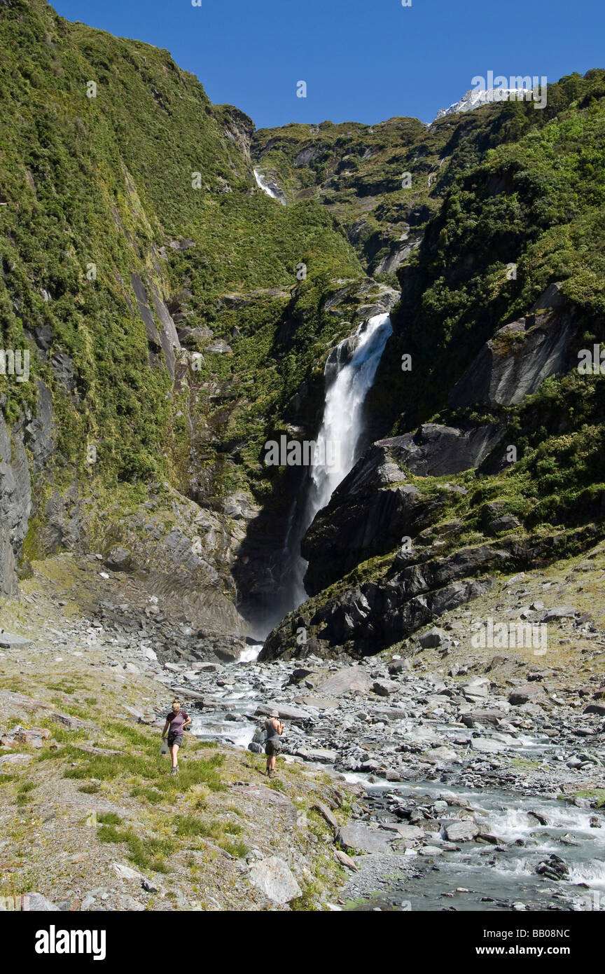 Hikers at waterfall in West Matukituki Valley Mount Aspiring National Park South Island New Zealand Stock Photo