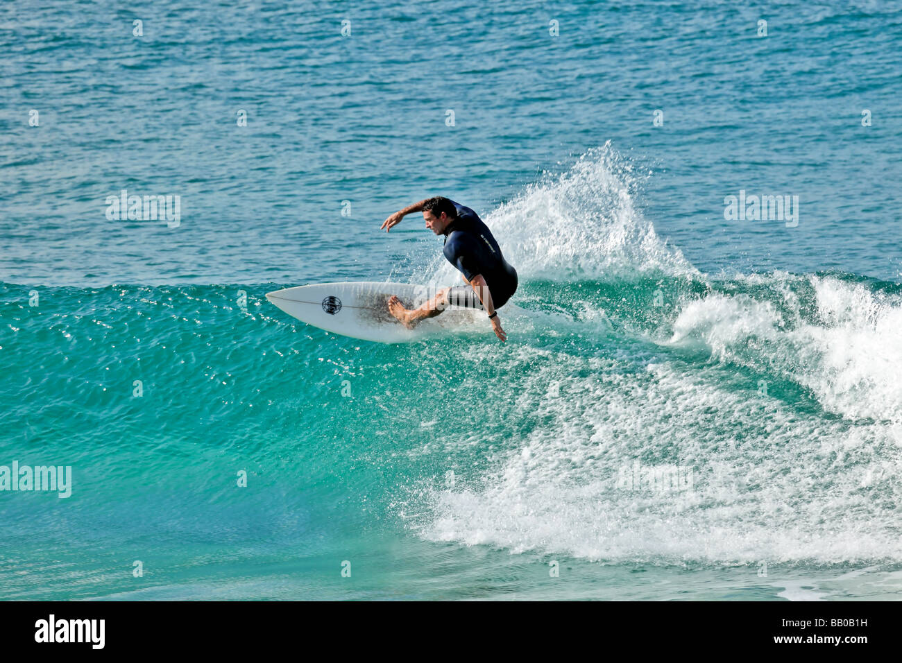 Male surfer on a surfboard catches a wave Stock Photo