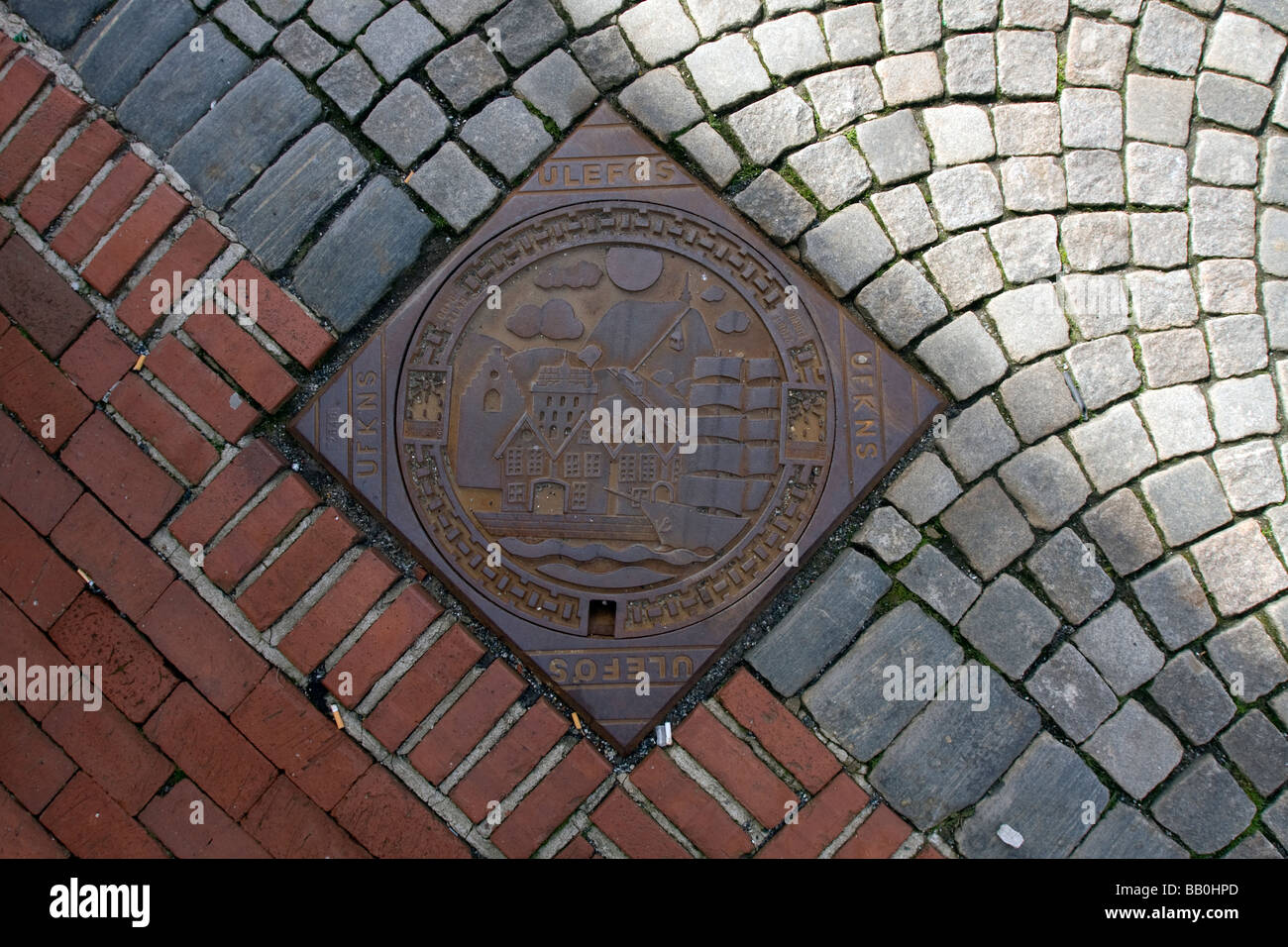 Decorated Drainage grate in the pavement of the Bryggen in Bergen, Norway Stock Photo