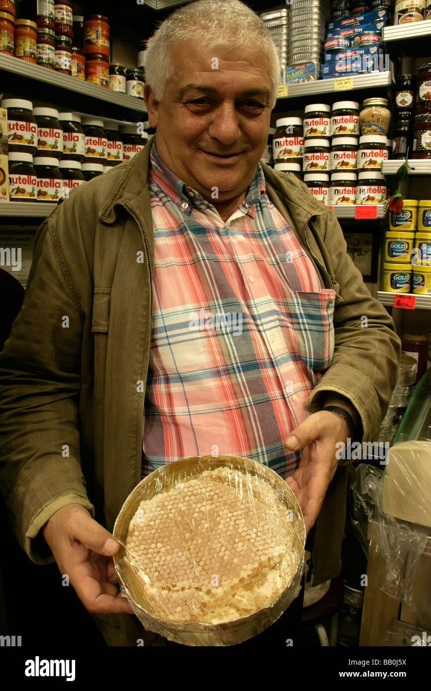 Turkish shopkeeper shows honey on the comb in his shop in Eminonu, Istanbul, Turkey Stock Photo