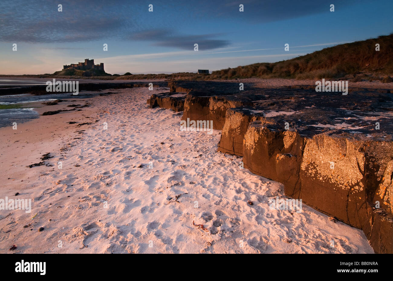 Rock Ledges and Bamburgh Castle in Morning light Stock Photo